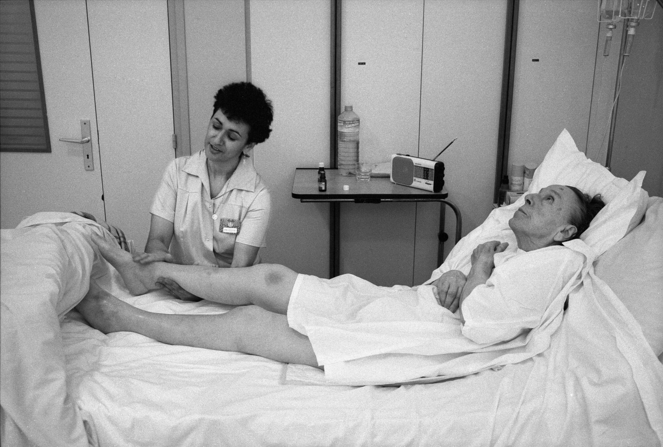 Soins Palliatifs. Maison médicale Jeanne Garnier. Une aide-soignante masse les jambes d'une malade. Paris.